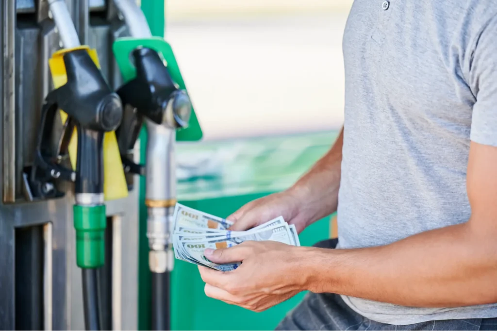 Man holding cash outside at gas pump